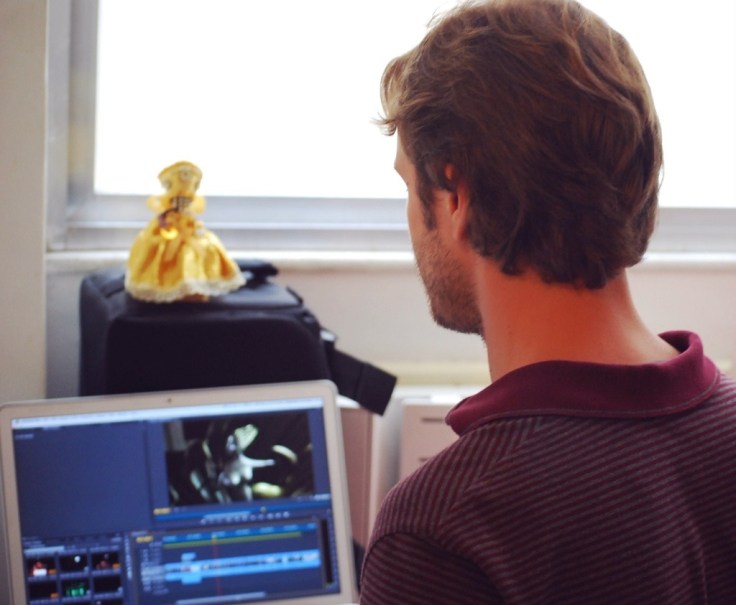 Editing one of his projects... An Orisha doll in a gold dress sits above his workstation